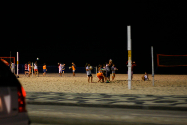 Pessoas jogando vôlei na praia a noite Pessoas jogando vôlei na praia a noite